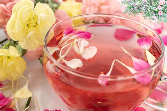 A teacup with flower petals and tea with a flower background for KCC event