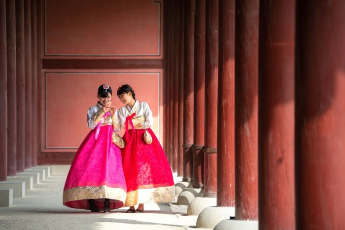 2 Koreans wearing hanboks while scrolling through their phone for the Korean Film Festival in Abu Dhabi this 2024