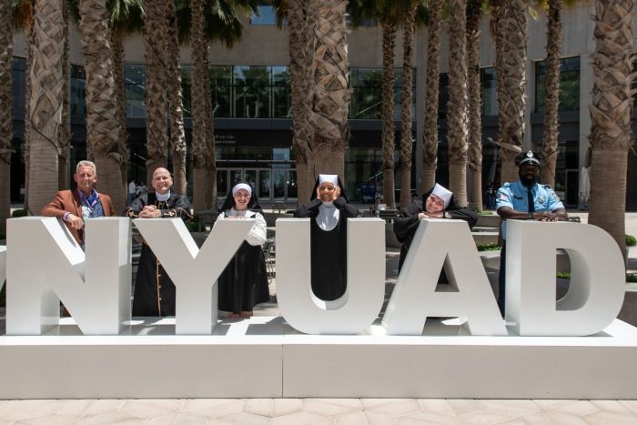 The casts of Sister Act the Musical at NYUAD Arts Center standing behind the big NYUAD letters, things to do in Abu Dhabi this weekend