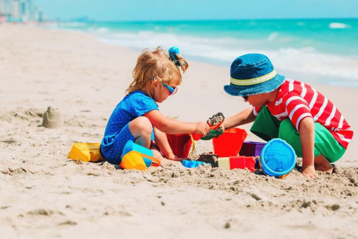 Kids on a beach playing with sand under the sun