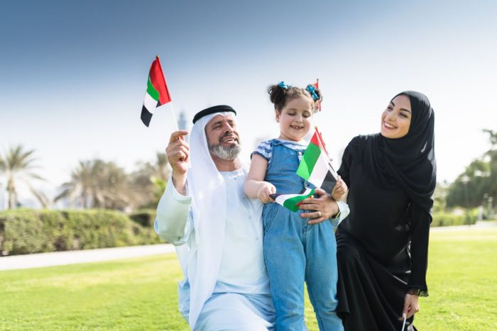 Emirati family waving a flag for UAE public holidays this 2025