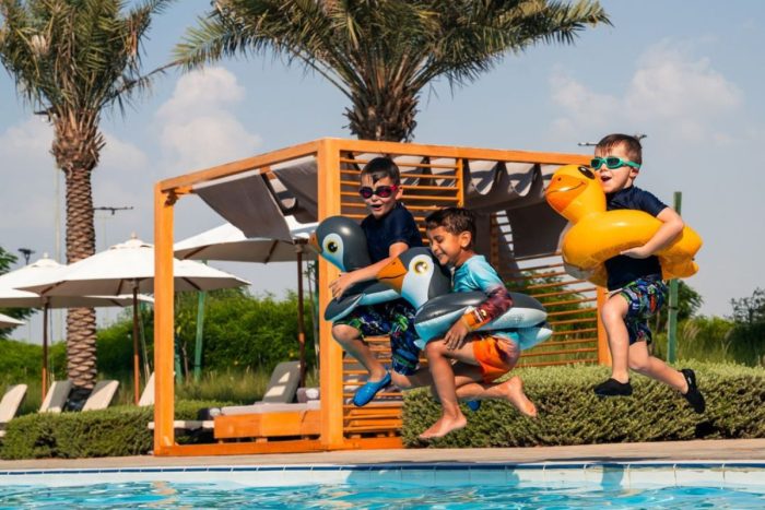 3 little boys jumping on the pool with their floaties at Yas ACres Golf and Country Club summer offers 2024