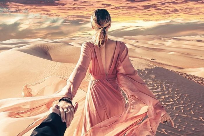 girl walking through the desert with her partner